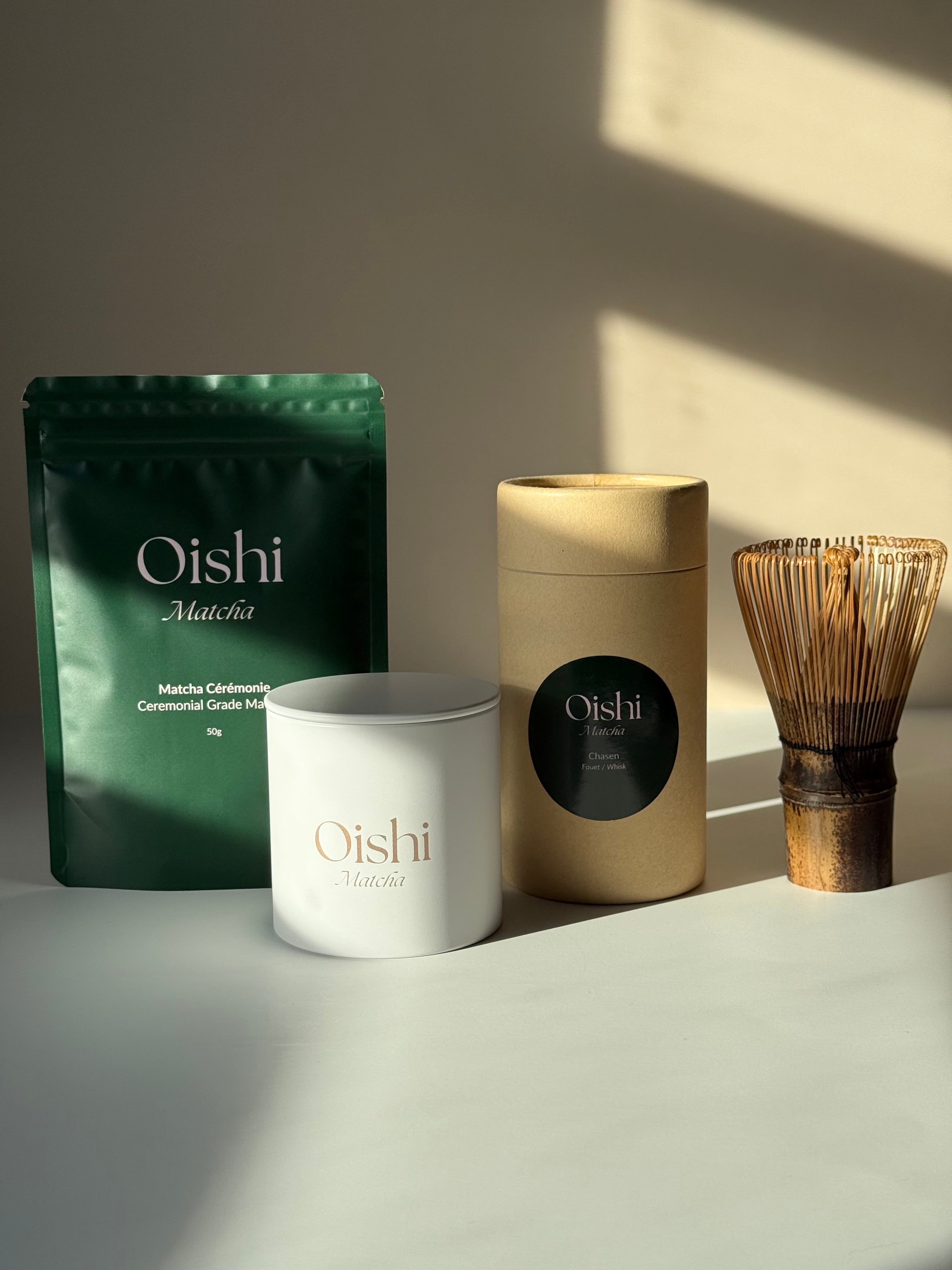 Ensemble comprenant le sachet Oishi Matcha de 50g, une boîte de stockage blanche avec logo doré et un fouet