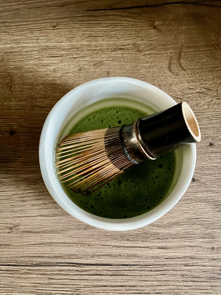 Bamboo whisk in a matcha bowl filled with foamy matcha